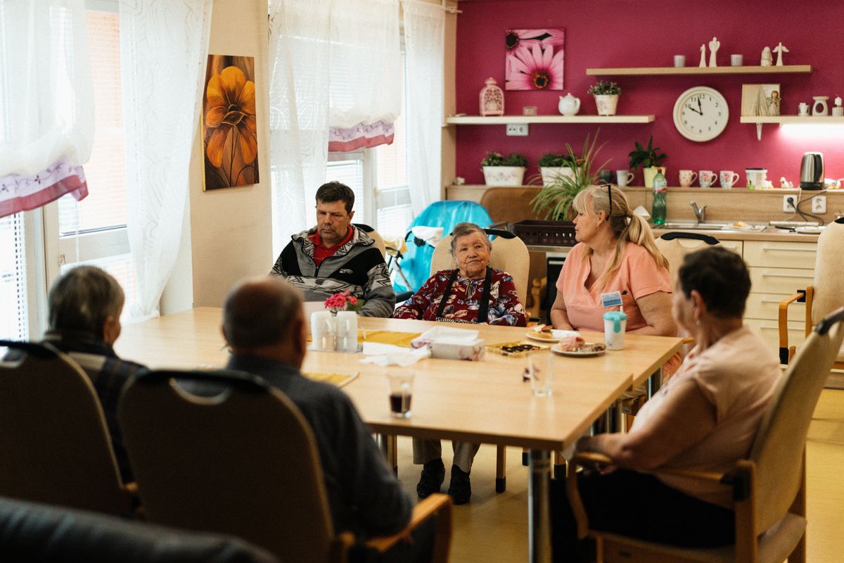 Seniors enjoying a meal together with caregiver support